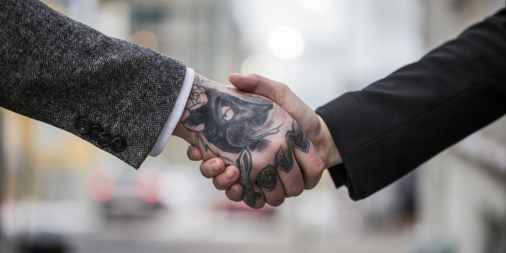 Cropped image of tattooed businessman greeting colleague